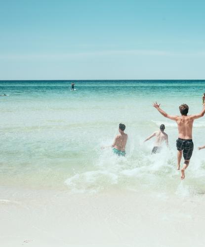 Persone corrono verso il mare in una giornata di sole.