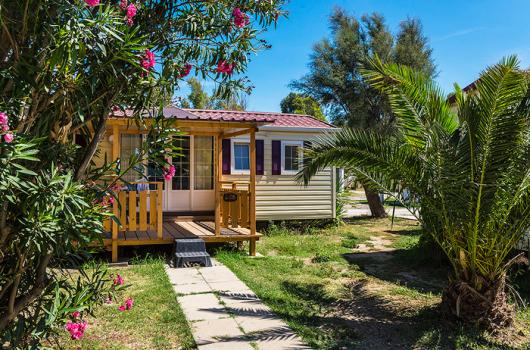 Bungalow accogliente circondato da piante tropicali e fiori colorati in un ambiente sereno.