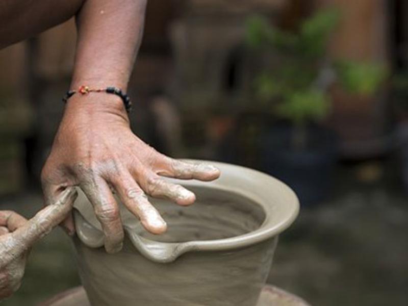 Mani che modellano un vaso di argilla su un tornio da ceramica.